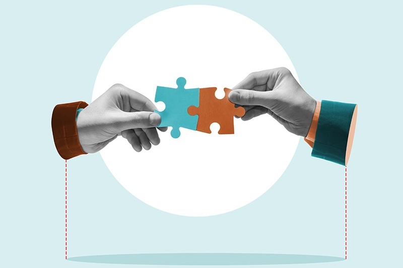 Dos manos uniendo piezas de un rompecabezas, simbolizando la colaboración entre el cliente y el proveedor de soporte de RPA.